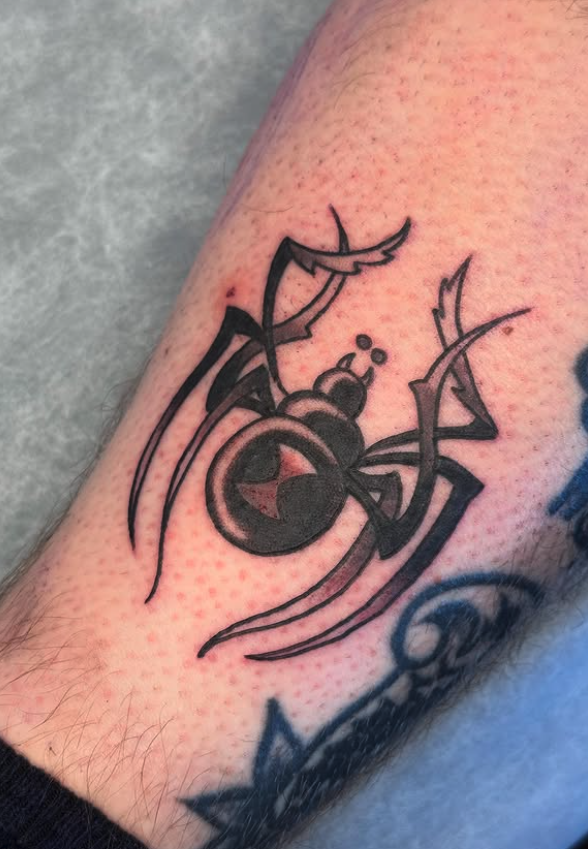 Black ink spider tattoo with a geometric style on a person's arm.
