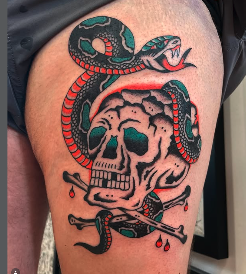 Tattoo of a skull with a snake wrapped around it and a crossbones underneath, with red drops around the design.
