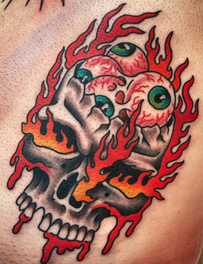 A colorful tattoo of a melting skull with three eyeballs and flames, in a neo-traditional style.