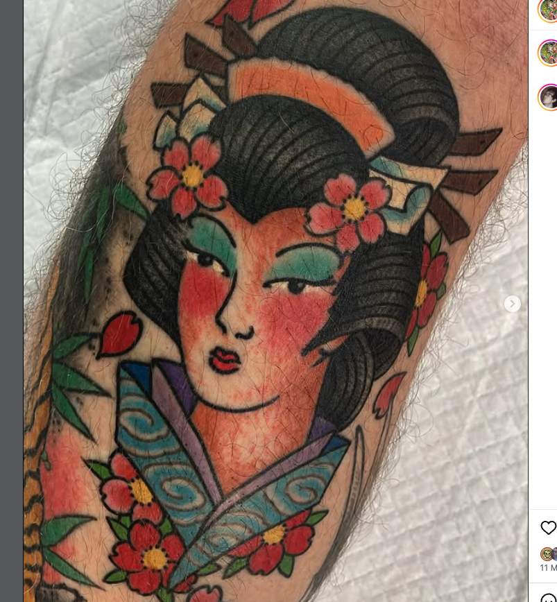 Tattoo of a geisha with traditional hairstyle, makeup, and flowers, surrounded by cherry blossoms and other floral elements.