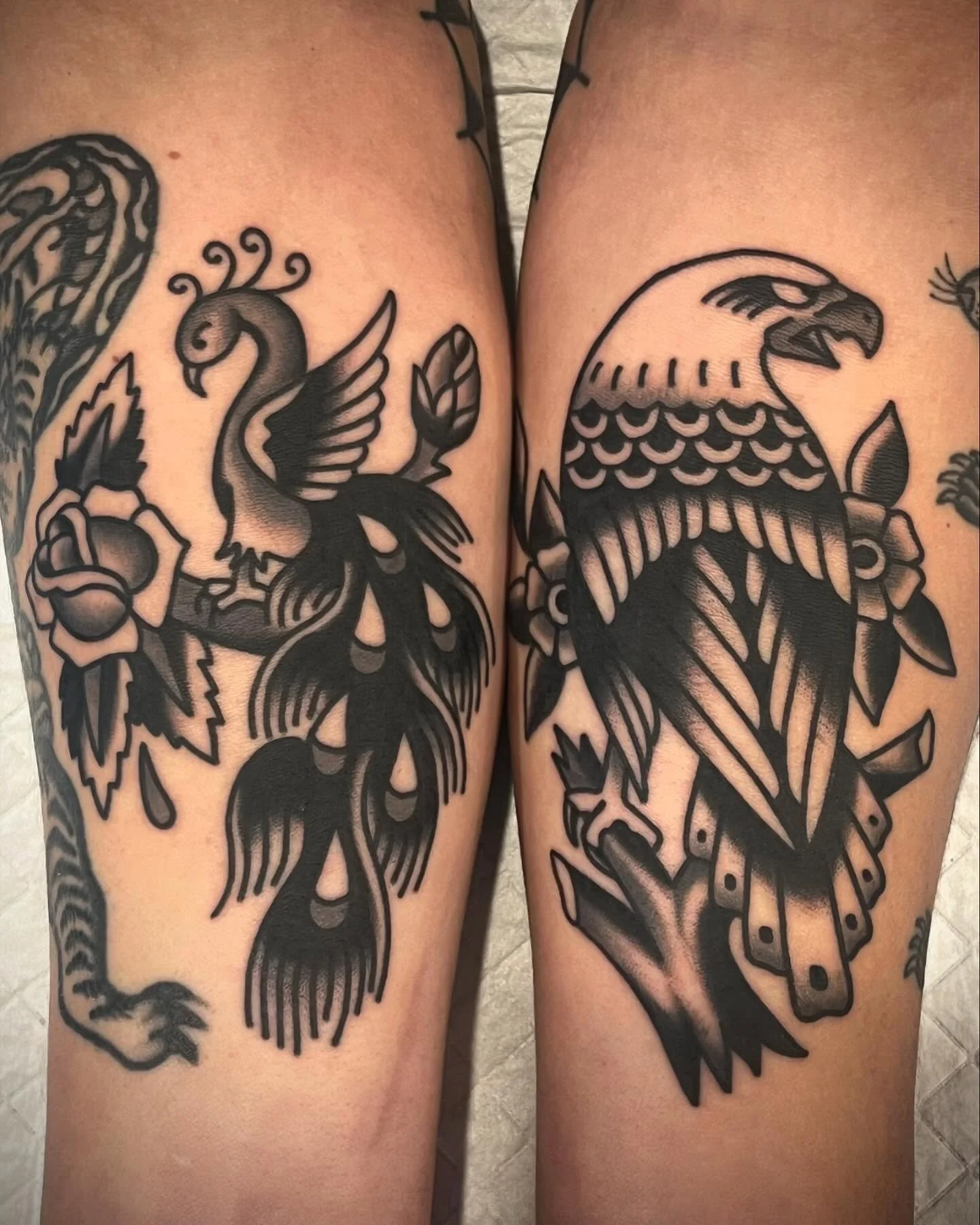 Tattoo of a swan surrounded by flowers on left thigh and eagle with leaves on right thigh.