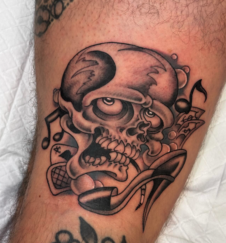 Tattoo of a skull with headphones, musical notes, and a pipe.