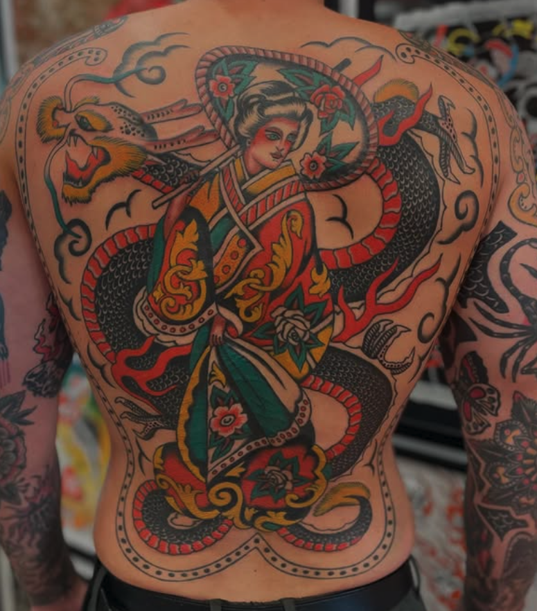 A colorful back tattoo depicting a woman in traditional Asian clothing, a dragon, and a large snake intertwined around her, with floral and decorative elements.