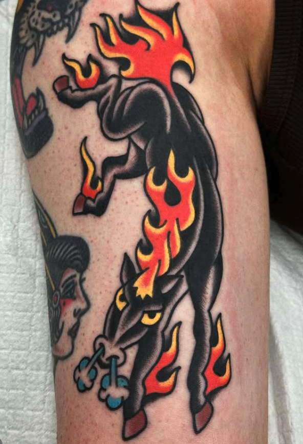 Tattoo of a stylized black horse with flames in red, yellow, and orange on its mane, tail, and hooves.