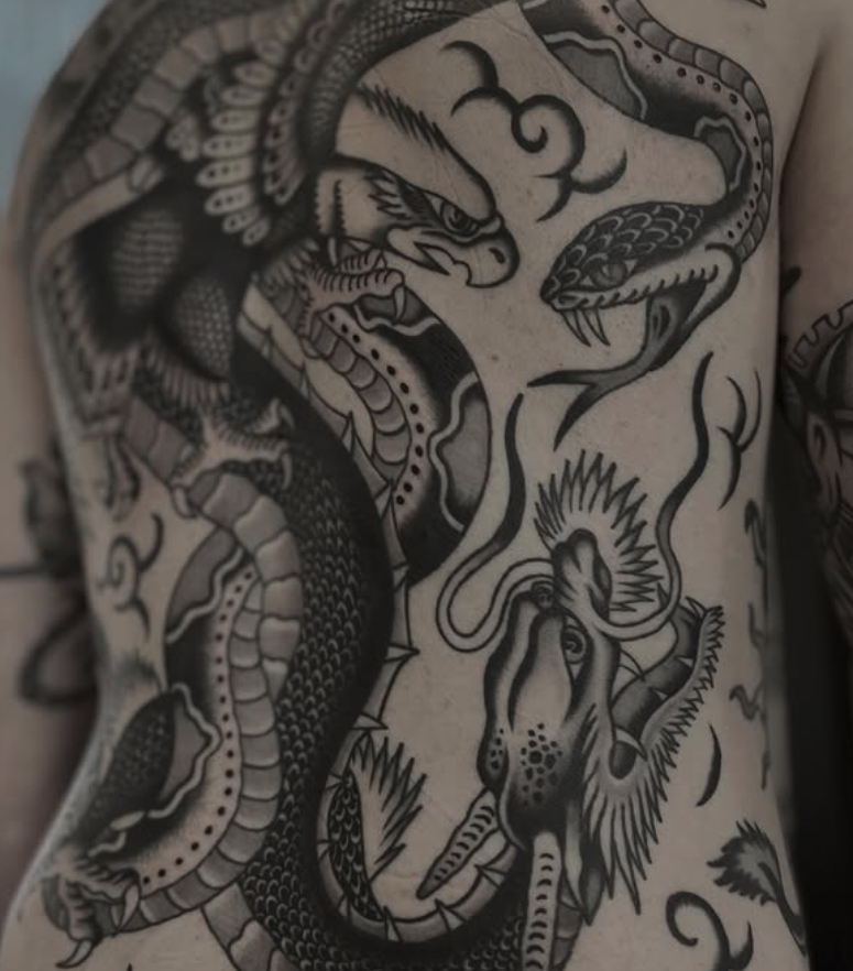 Black and gray tattoo of a fierce dragon and a serpent intertwined on a person's chest.