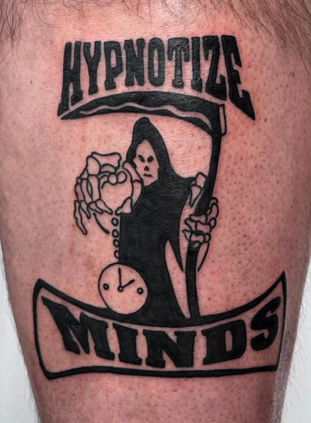 Tattoo featuring the words 'HYPNOTIC MINDS' with an image of a woman in black holding a scythe, a pocket watch, and a banner with the text.