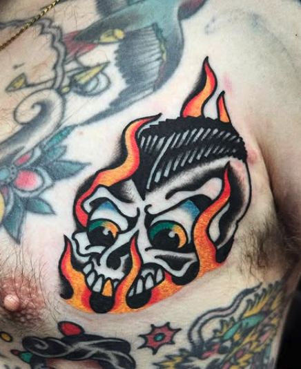 Tattoo of a skull with flames above the chest