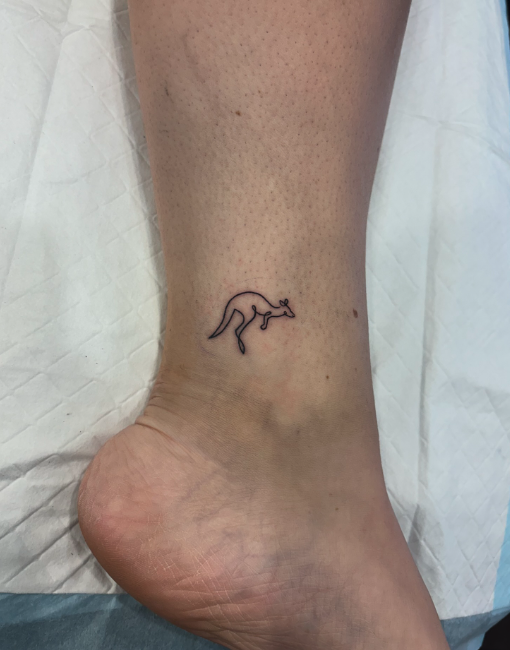 Close-up of a person's ankle with a small outline tattoo of a kangaroo on the side.