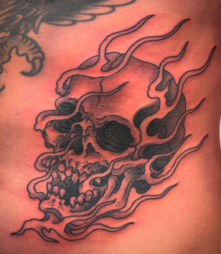 Tattoo of a skull with flowing lines and shading details.