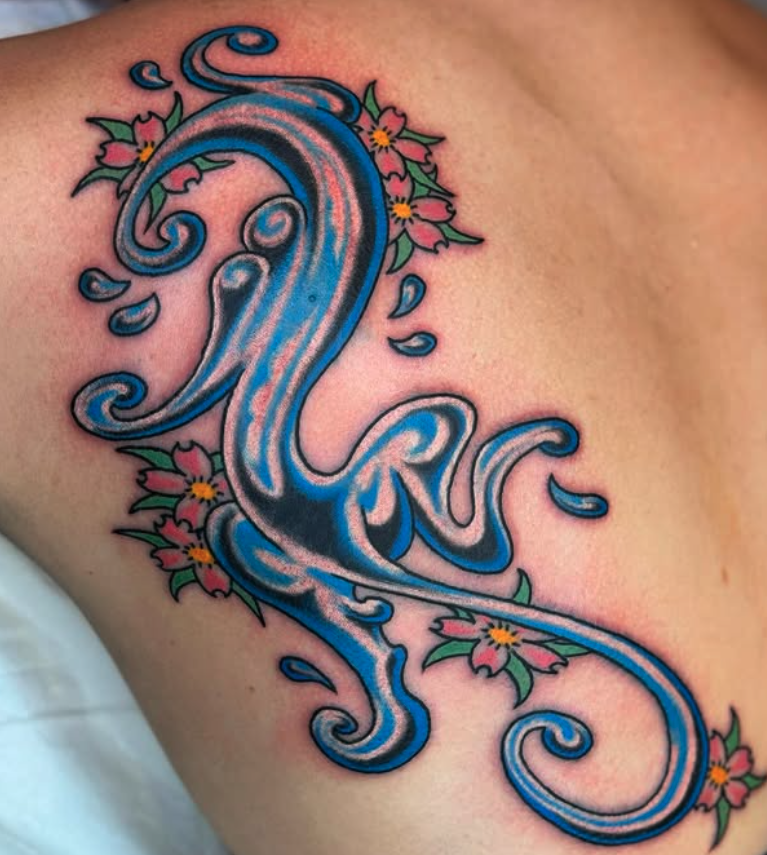 Tattoo of a stylized blue wave with pink flowers and green leaves surrounding it.