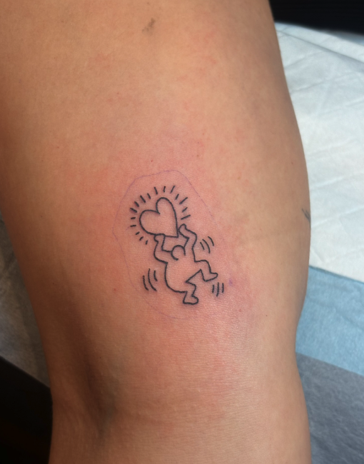 Temporary tattoo of a jumping baby holding a heart, with lines indicating movement and a dashed outline.