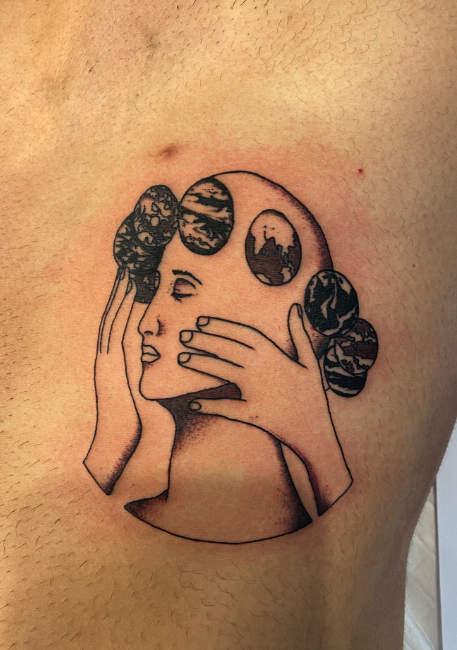 Tattoo of a woman's face with closed eyes, holding her head with one hand, and five abstract circular designs above her head.