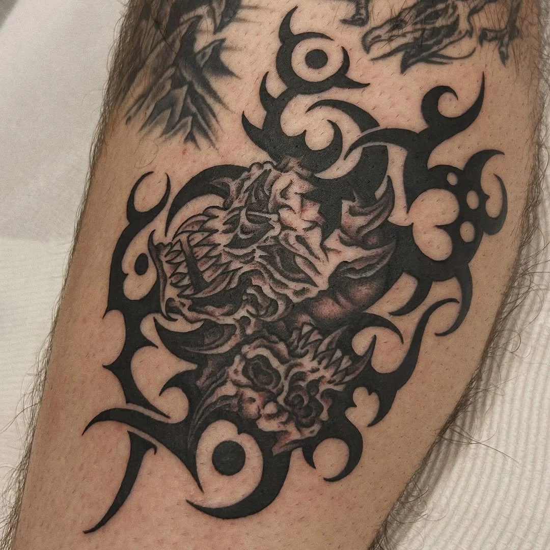 Black tribal-style tattoo of a fierce tiger head with detailed shading on a person's arm.