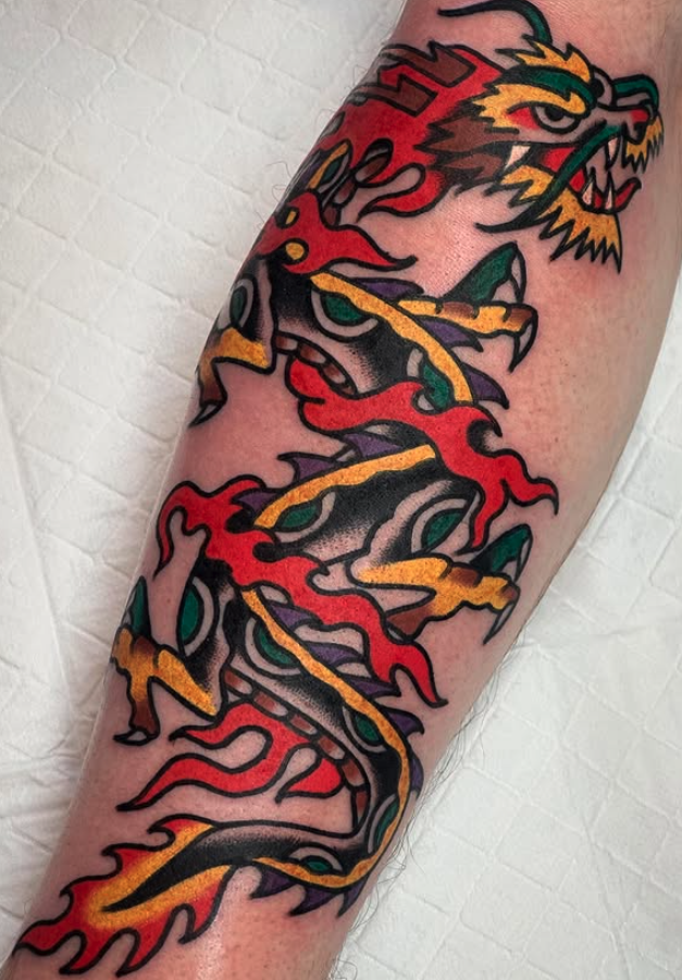 Tattoo of a colorful dragon with bold black outlines, featuring red, yellow, purple, and green accents, on a person's forearm.