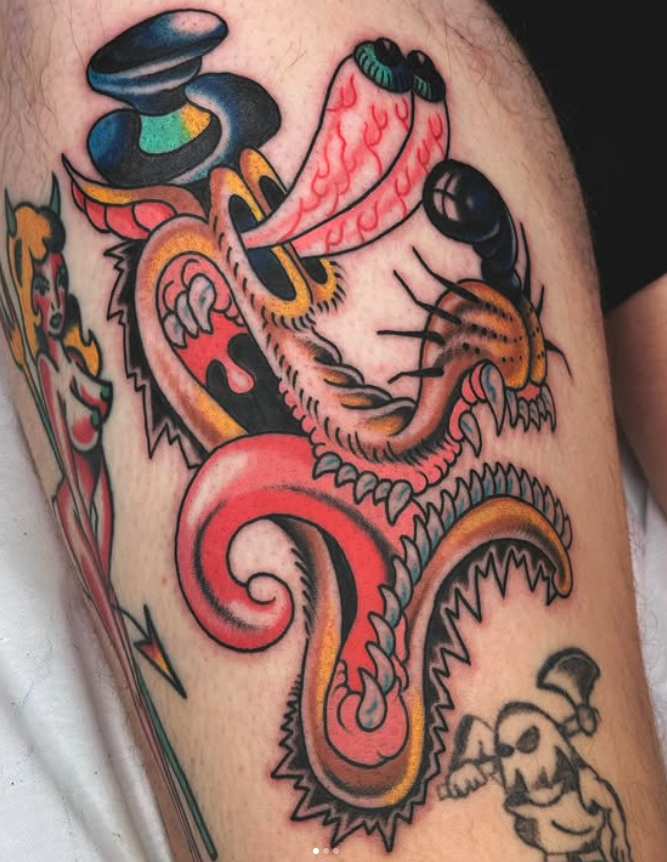 Colorful tattoo featuring a snake with open mouth, sharp teeth, and tongue out, intertwined with a tiger's face, with a skull with sunglasses at the bottom
