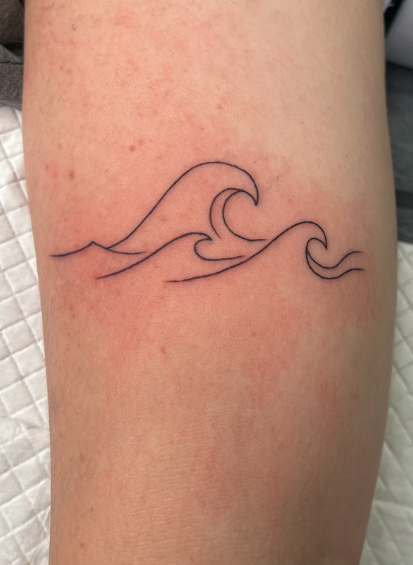 Line art tattoo of ocean waves on skin.