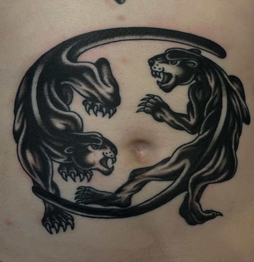 Tattoo of two black panthers facing each other in a circular pose.