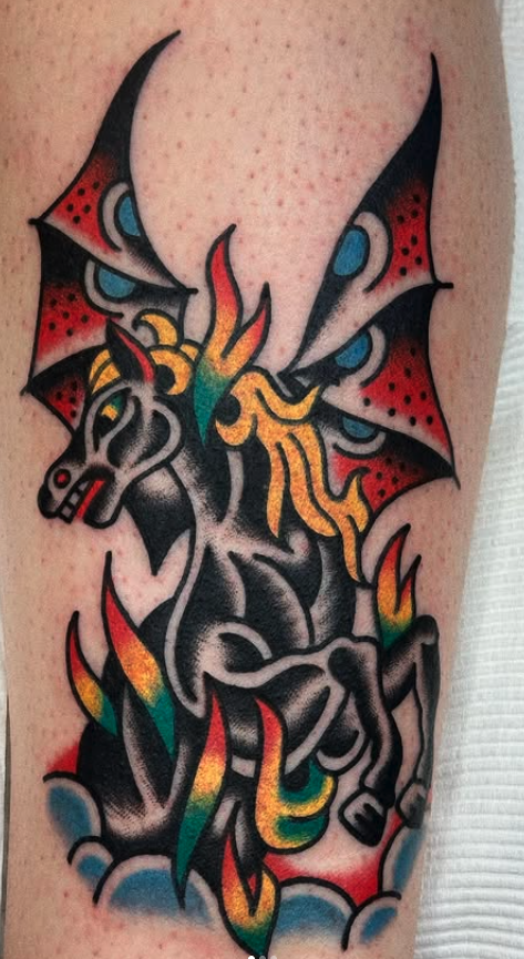 Colorful tattoo of a dragon with bat-like wings on person's arm.