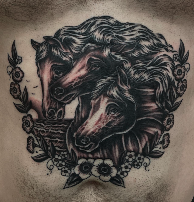Tattoo of two horses' heads surrounded by flowers on a person's chest.