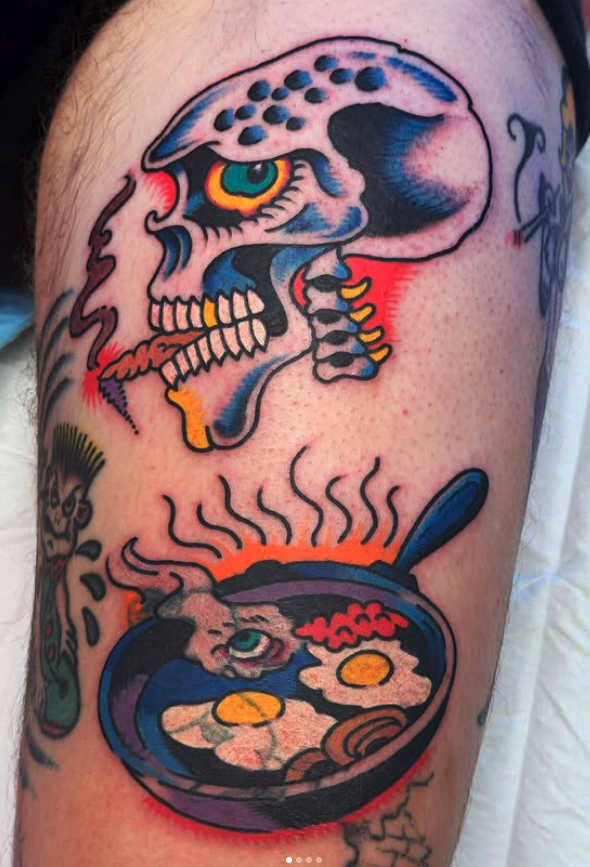 Tattoo of a skull with colorful accents above a steaming bowl of ramen with a cartoon rabbit inside.