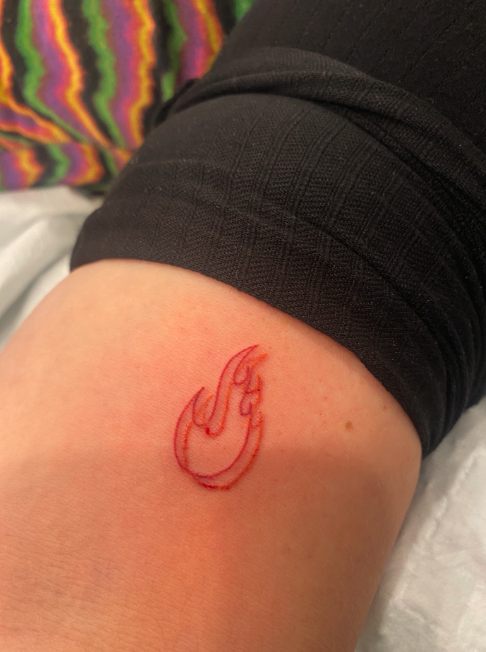A small tattoo of a flame on a person's forearm.