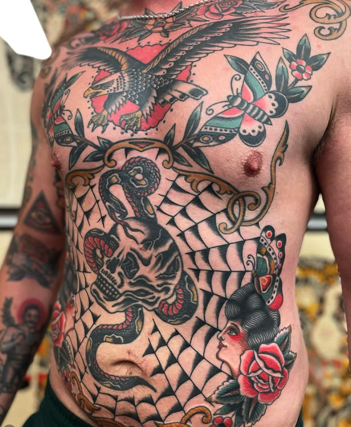 Tattooed man's chest featuring a large snake, a skull, a hawk, a bee, roses, and web patterns in traditional tattoo style.