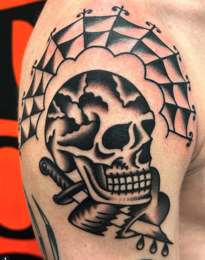 A black and gray tattoo of a skull with a swirling cloud inside it, a dagger pierced through the skull's side, and a spider web pattern above it.