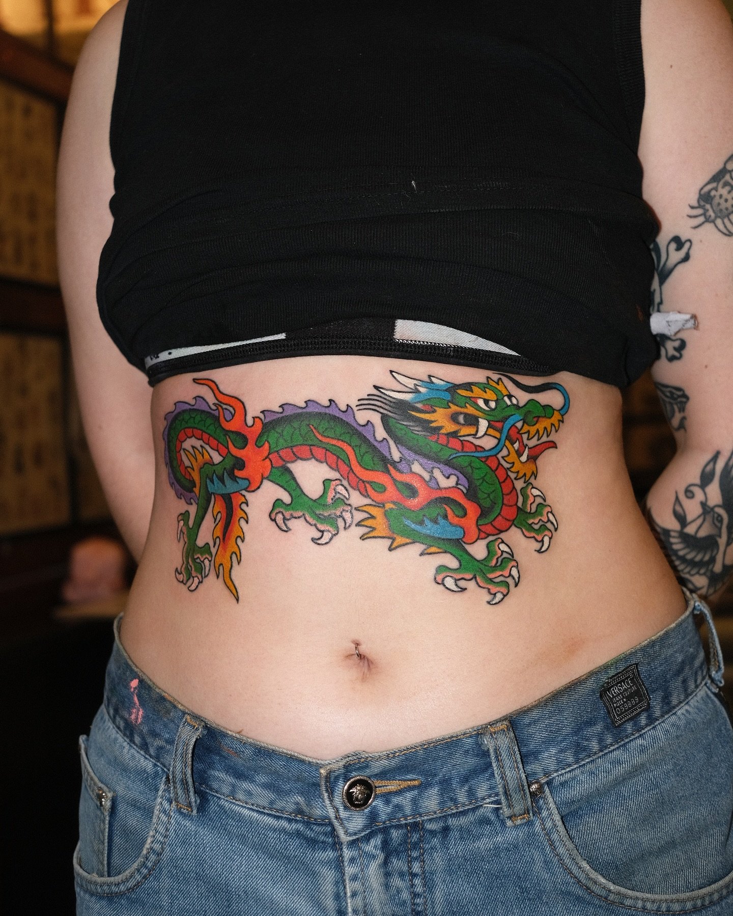 Colorful tattoo of a dragon on a person's waist.