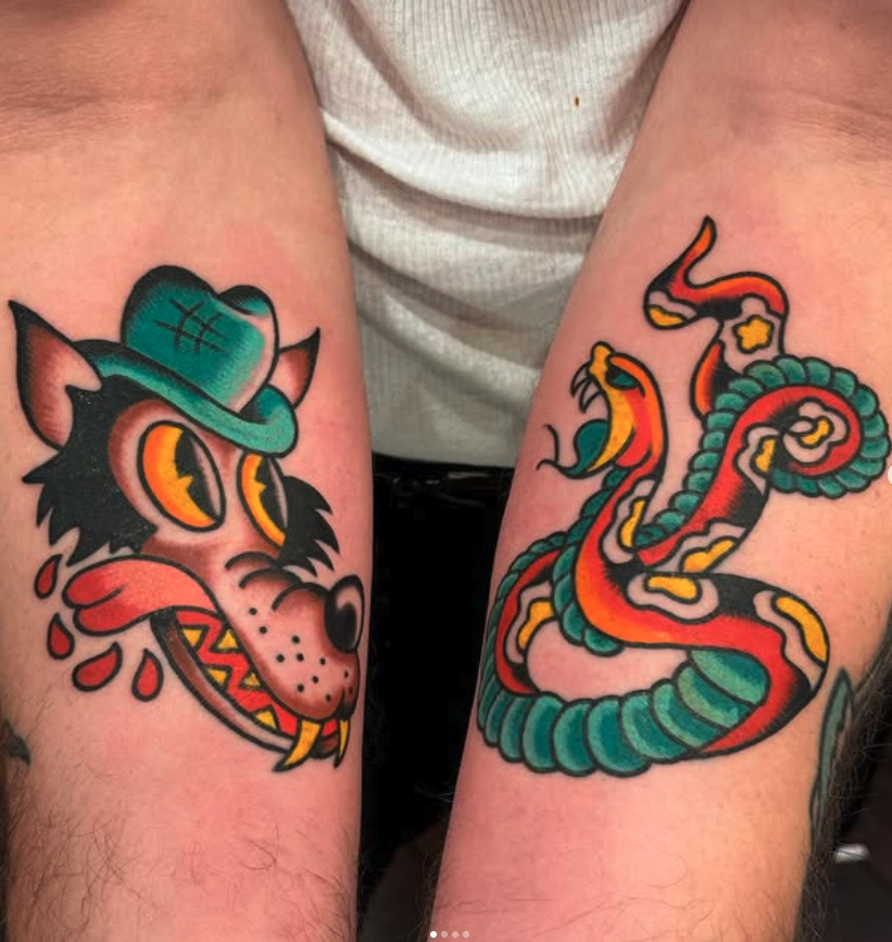 Tattoo of a dog wearing a teal hat, with blood tears and a mischievous expression, on the left arm. Tattoo of a colorful, stylized snake with red, yellow, green, and black markings, on the right arm.