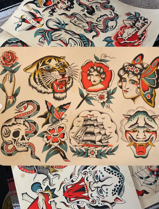 Collection of various traditional and modern tattoo flash designs including a tiger, a woman with flowers, a butterfly, a skull with a snake, a ship, a clown, a snake, a rose, and other colorful images.
