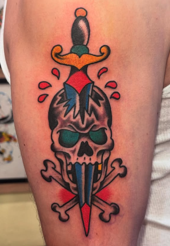 Tattoo of a skull with lightning bolt eyes, a sword through the top, and crossed bones behind, in a traditional tattoo style.