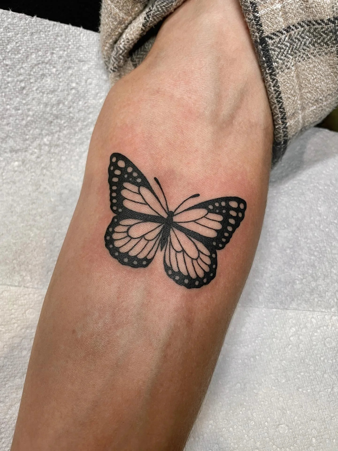 Freshly inked black and peach butterfly tattoo on upper arm
