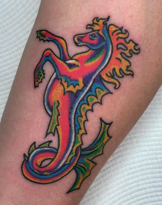 Colorful tattoo of a seahorse with rainbow hues on the arm.