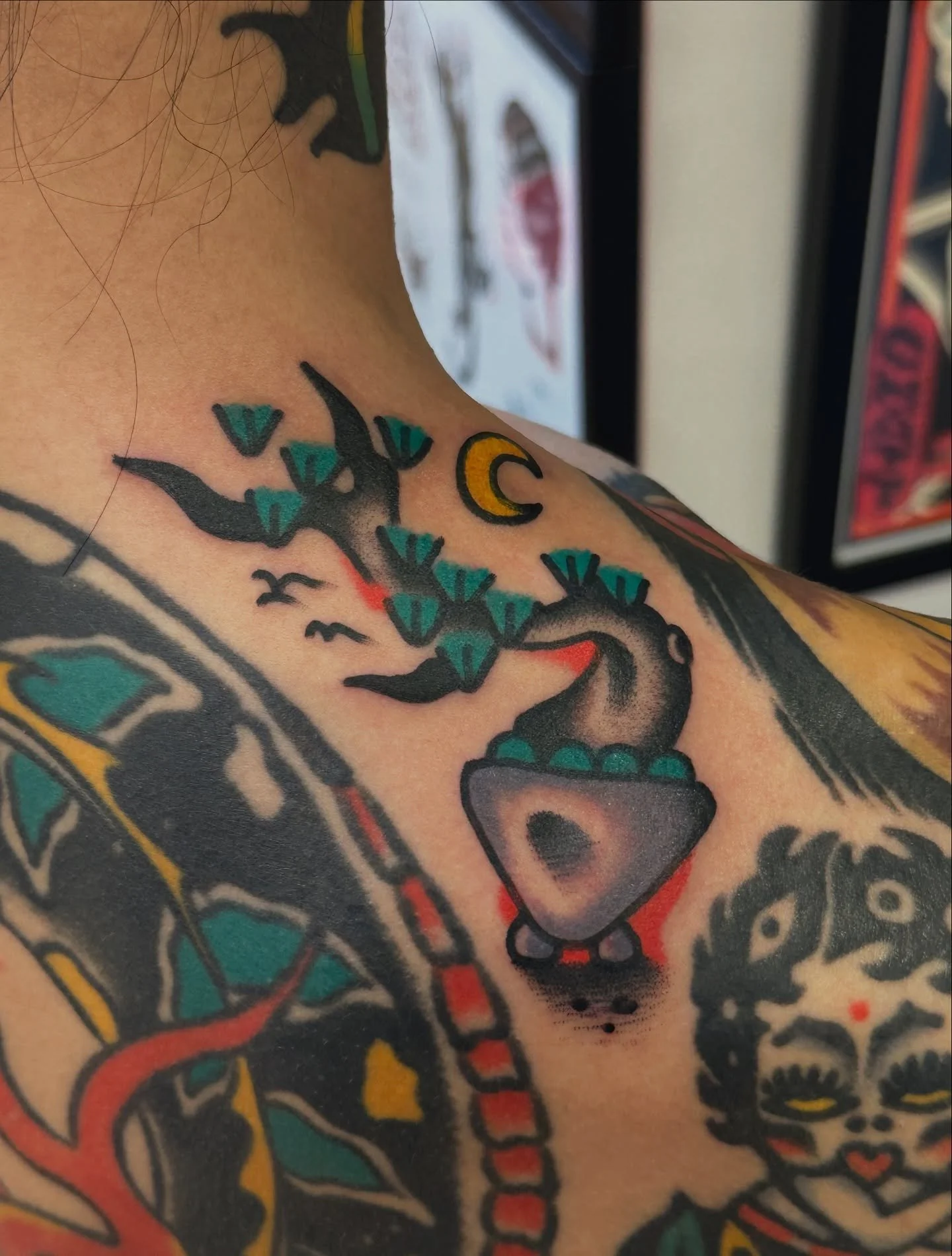 Close-up of a colorful tattoo on a person's shoulder, featuring a black and gray ankh with a snake entwined, set in traditional tattoo style.