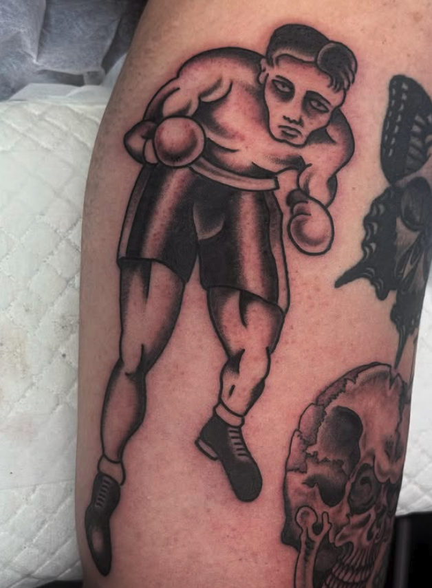 Tattoo of a muscular boxer in boxing shorts and gloves, standing with fists raised.