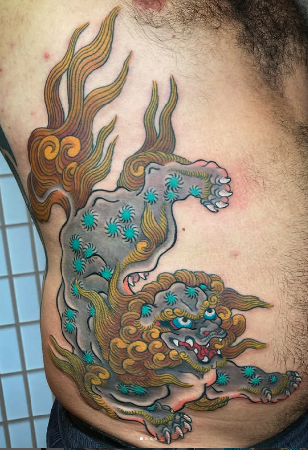 Colorful tattoo of a mythological lion with a fiery mane on a person's side.