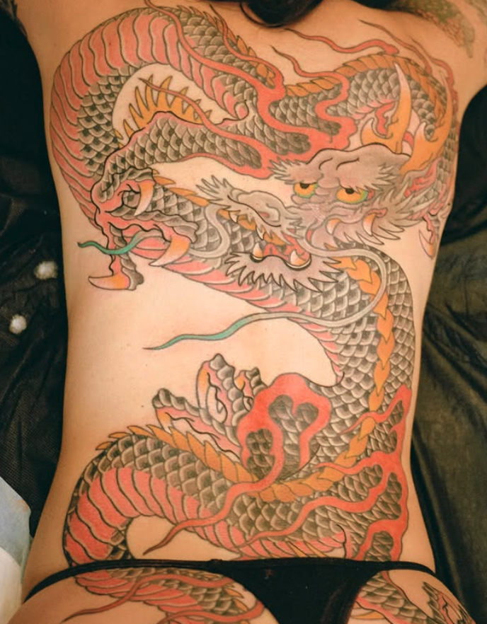 A colorful tattoo of a traditional Asian dragon covering the person's chest and abdomen, featuring scales, claws, and a fierce expression.