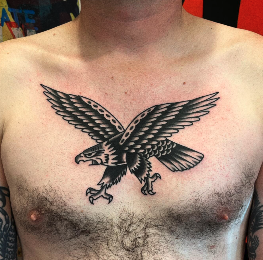 A black and gray tattoo of an eagle with outstretched wings on a man's chest.