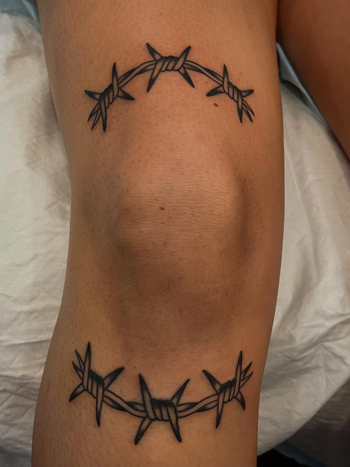 Tattoo of a barbed wire circle on a person's arm.