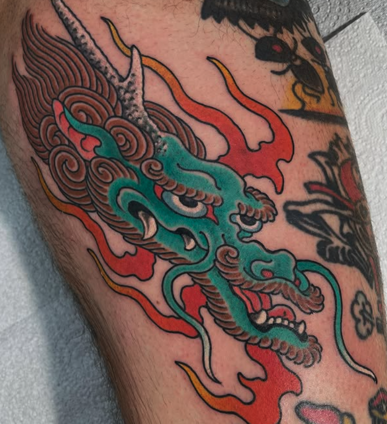 Colorful traditional Japanese dragon tattoo on skin, with detailed scales, whiskers, and flames.