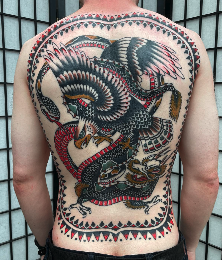 Colorful traditional Japanese tattoo of a dragon and a phoenix intertwined on a person's back.