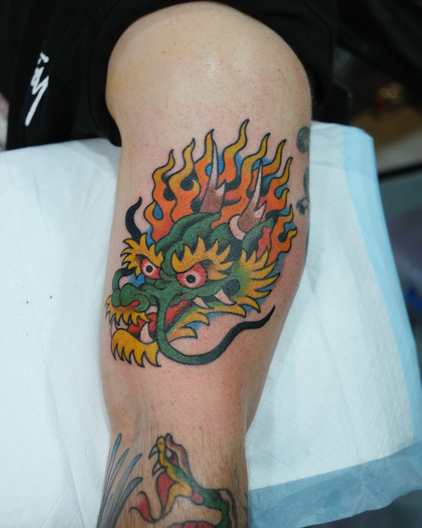 A colorful tattoo of a traditional Asian-style dragon on a person's upper arm.