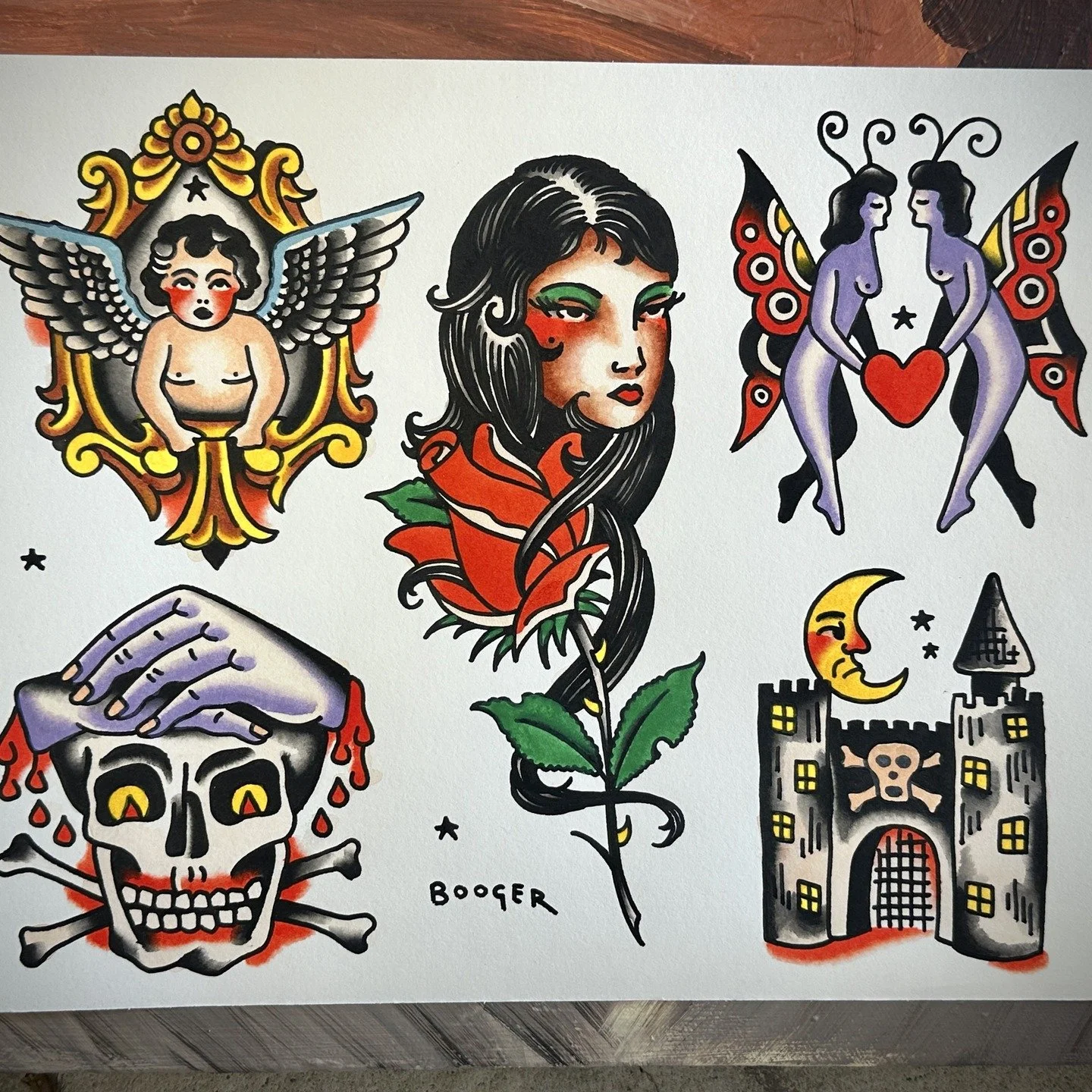 Collection of tattoo-style illustrations including a winged cherub with a star, a woman with long black hair and a red flower, two women with butterfly wings holding a red heart, a spooky castle with a yellow moon and a bat symbol, a grinning skull w
