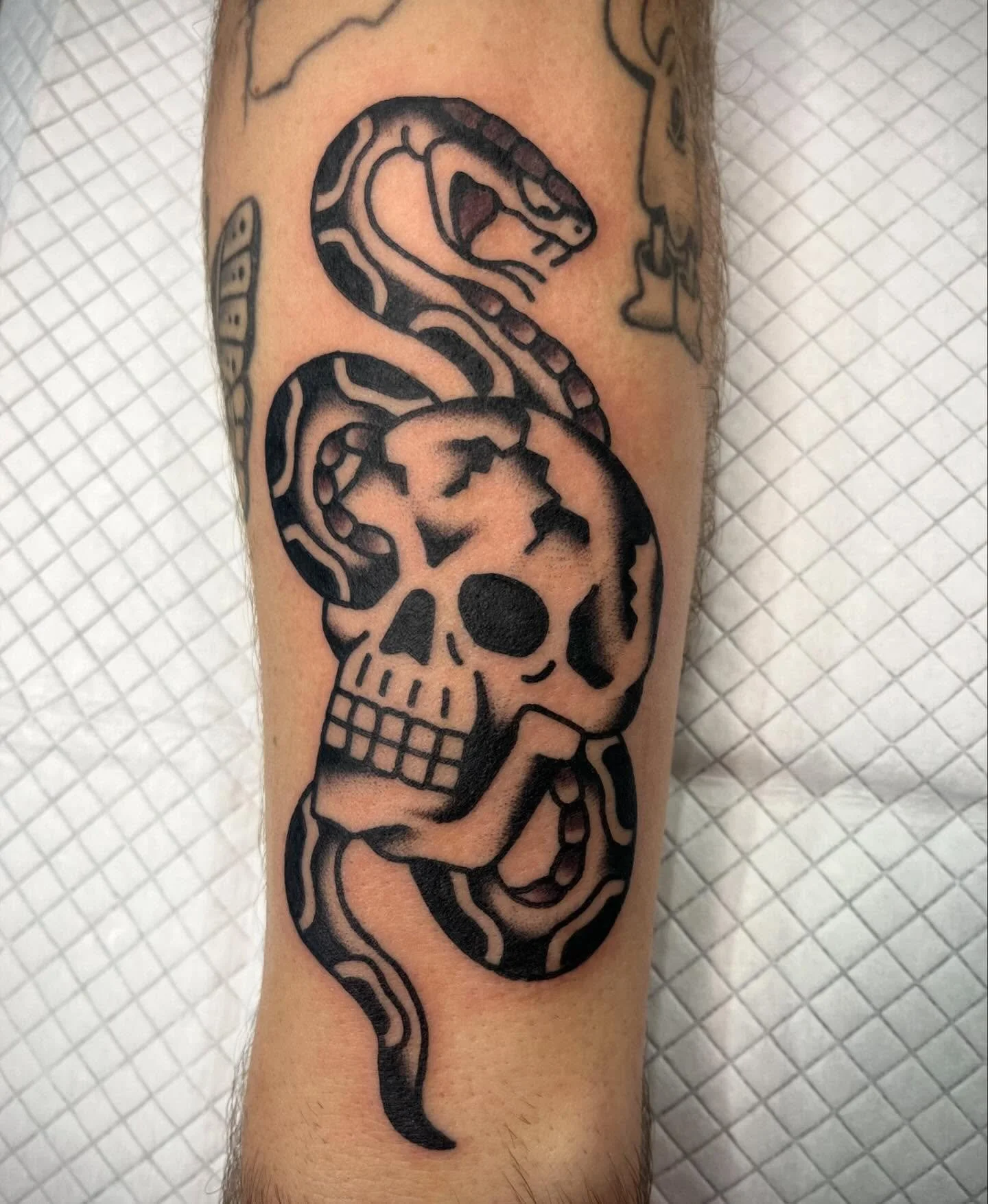 Tattoo of a skull with a snake wrapping around it.
