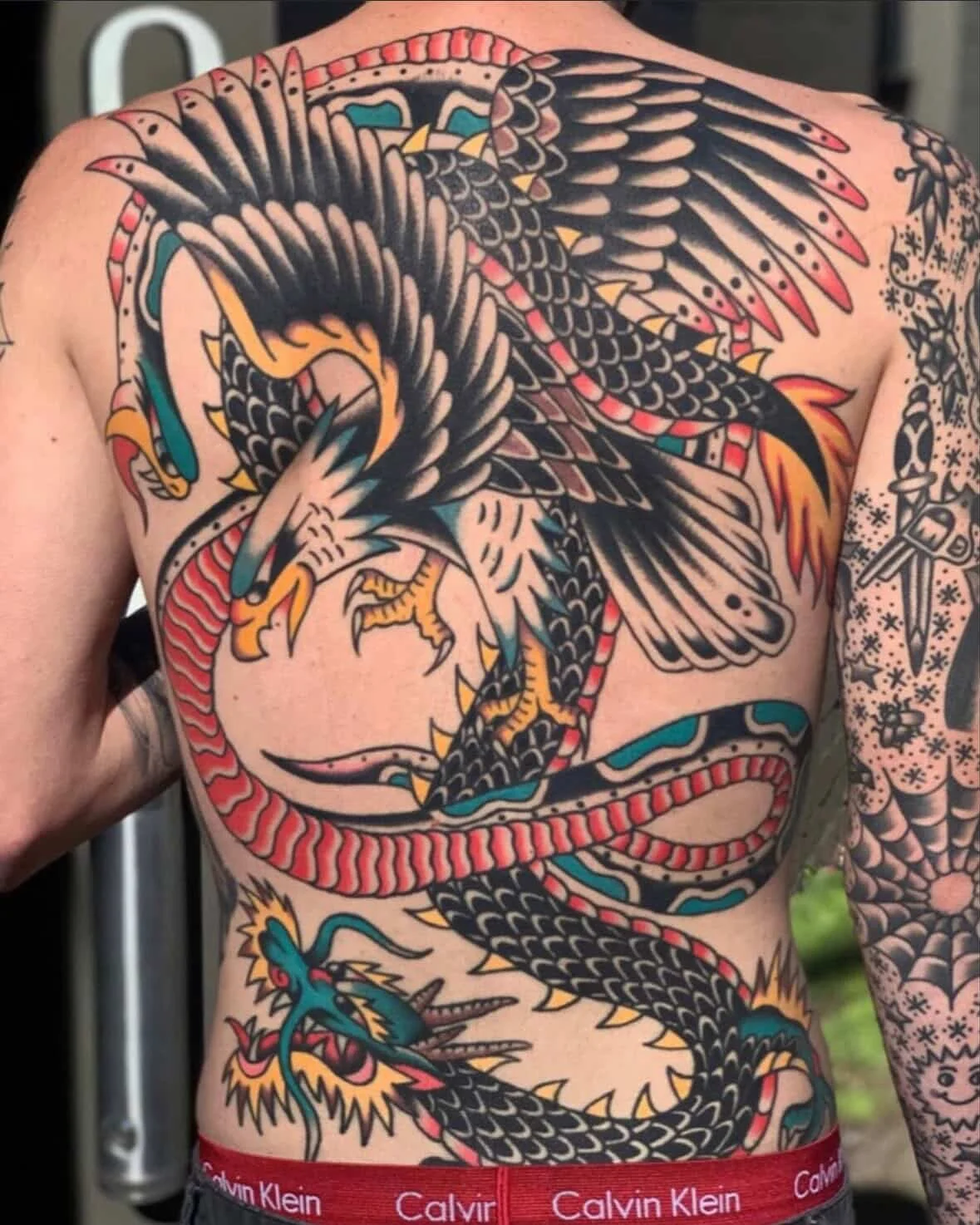 Tattoo of a traditional Japanese style dragon covering the person's chest and torso, with bright colors and detailed scales.