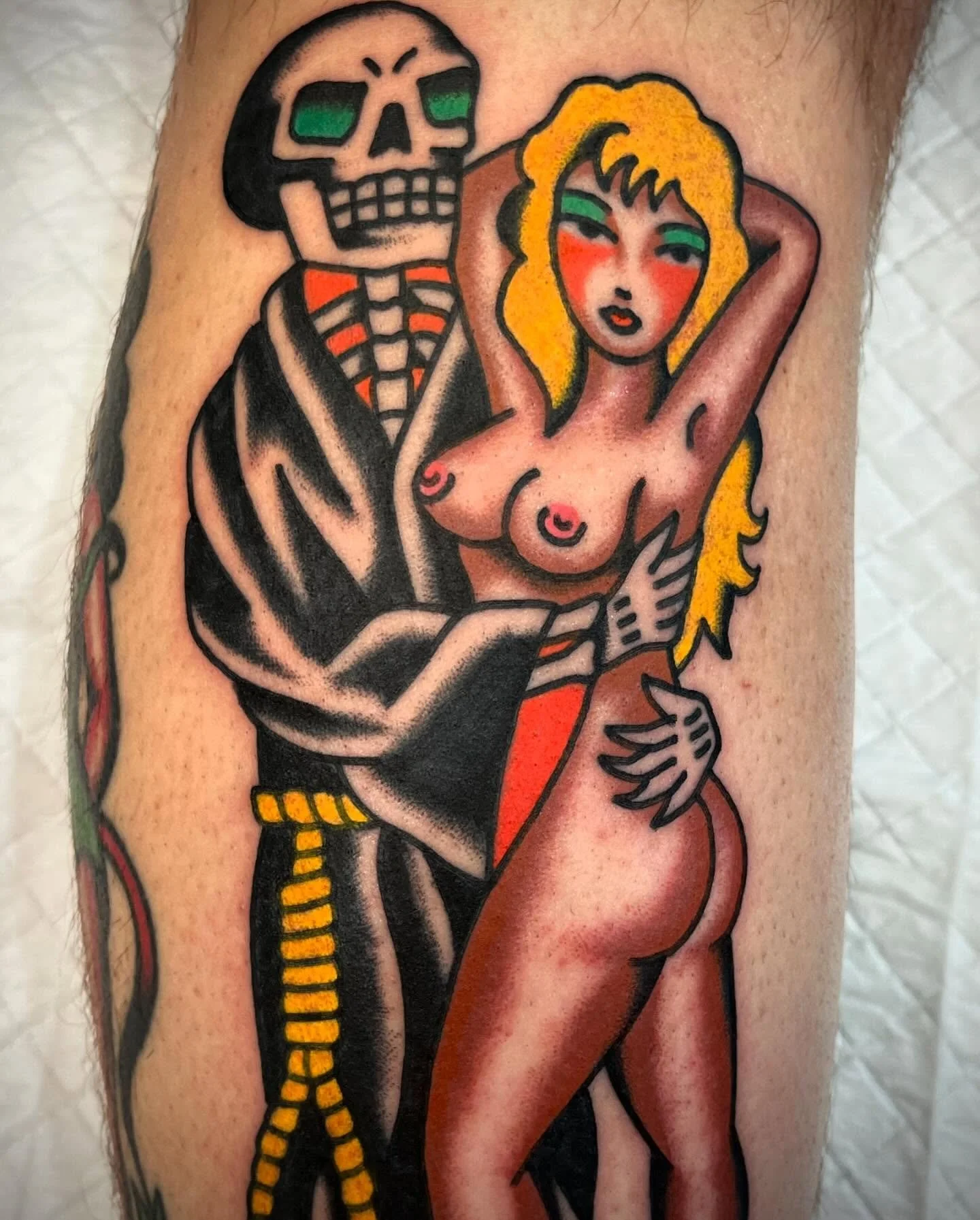 Tattoo of a skeleton and a woman with long blonde hair, one arm behind her head, on skin