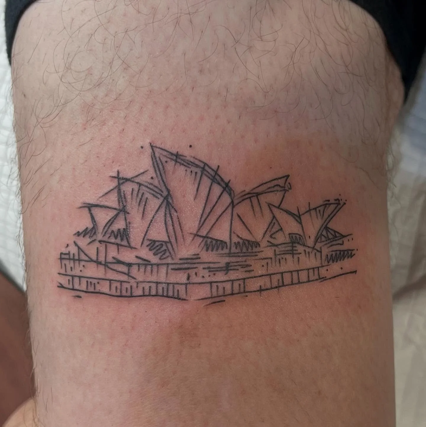 Tattoo sketch of the Sydney Opera House on a person's upper arm.