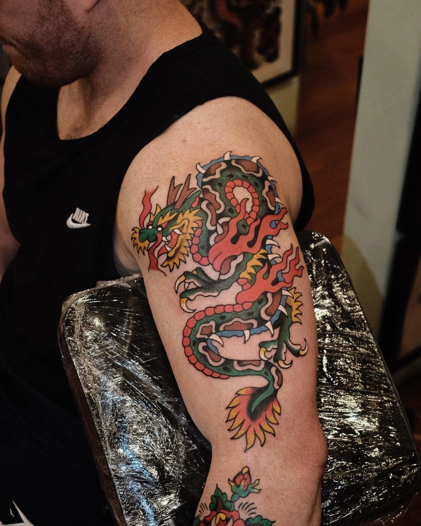 A tattoo of a traditional Asian dragon on a person's upper arm with vibrant colors and detailed features.