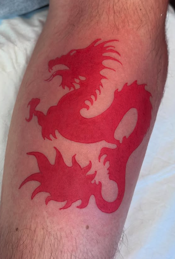 Red dragon tattoo on a person's leg.