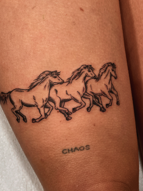 Tattoo of three running horses above the word 'CHAOS' on skin.